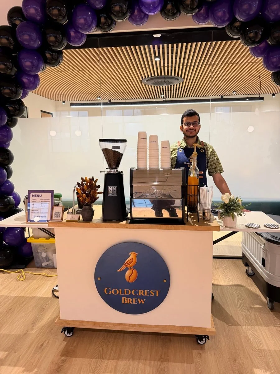 Founder Zain at the Goldcrest Brew coffee cart under a balloon arch at a San Francisco office event