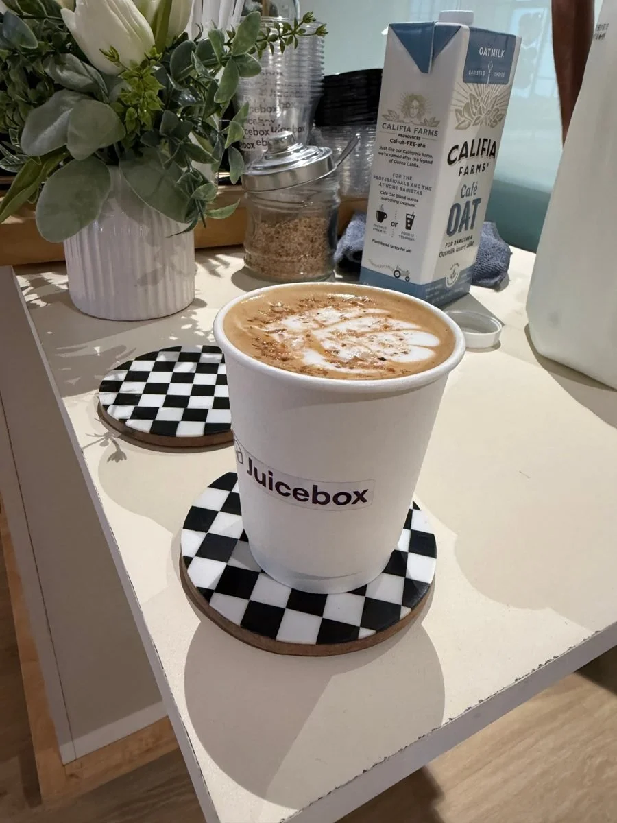 Latte in a Juicebox-branded cup on a checkered coaster