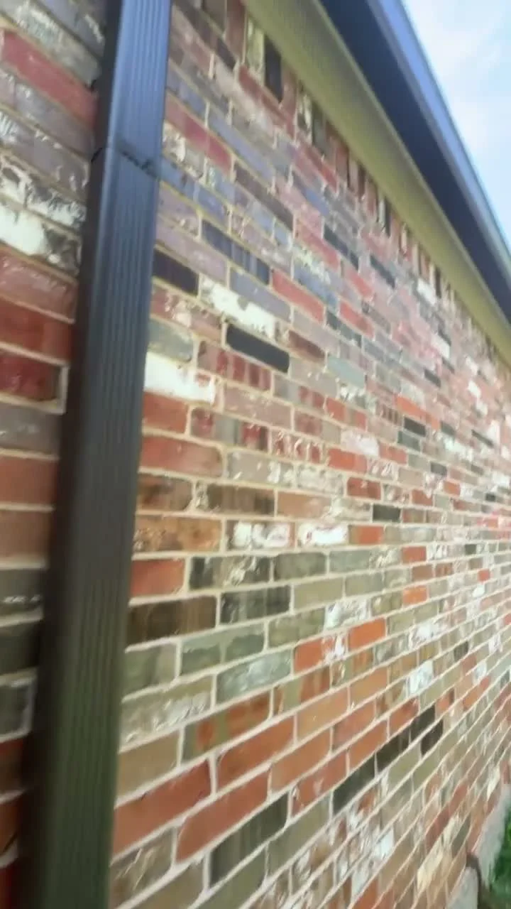 Client-supplied view of a gutter downspout beside a brick home