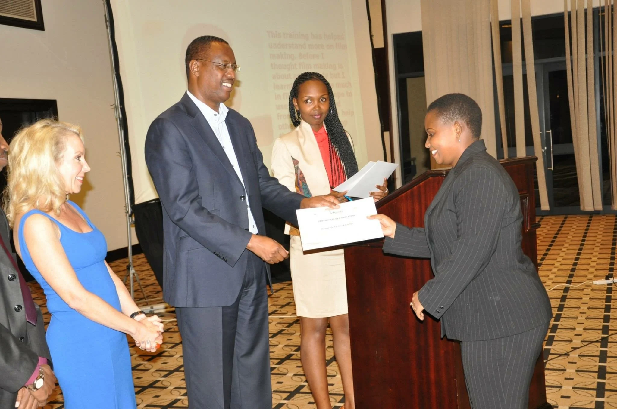 A graduate receives her certificate at the Umbrella Cinema Promoters launch, with a Rwandan government official and international partners present, Kigali Serena Hotel, March 24, 2013.