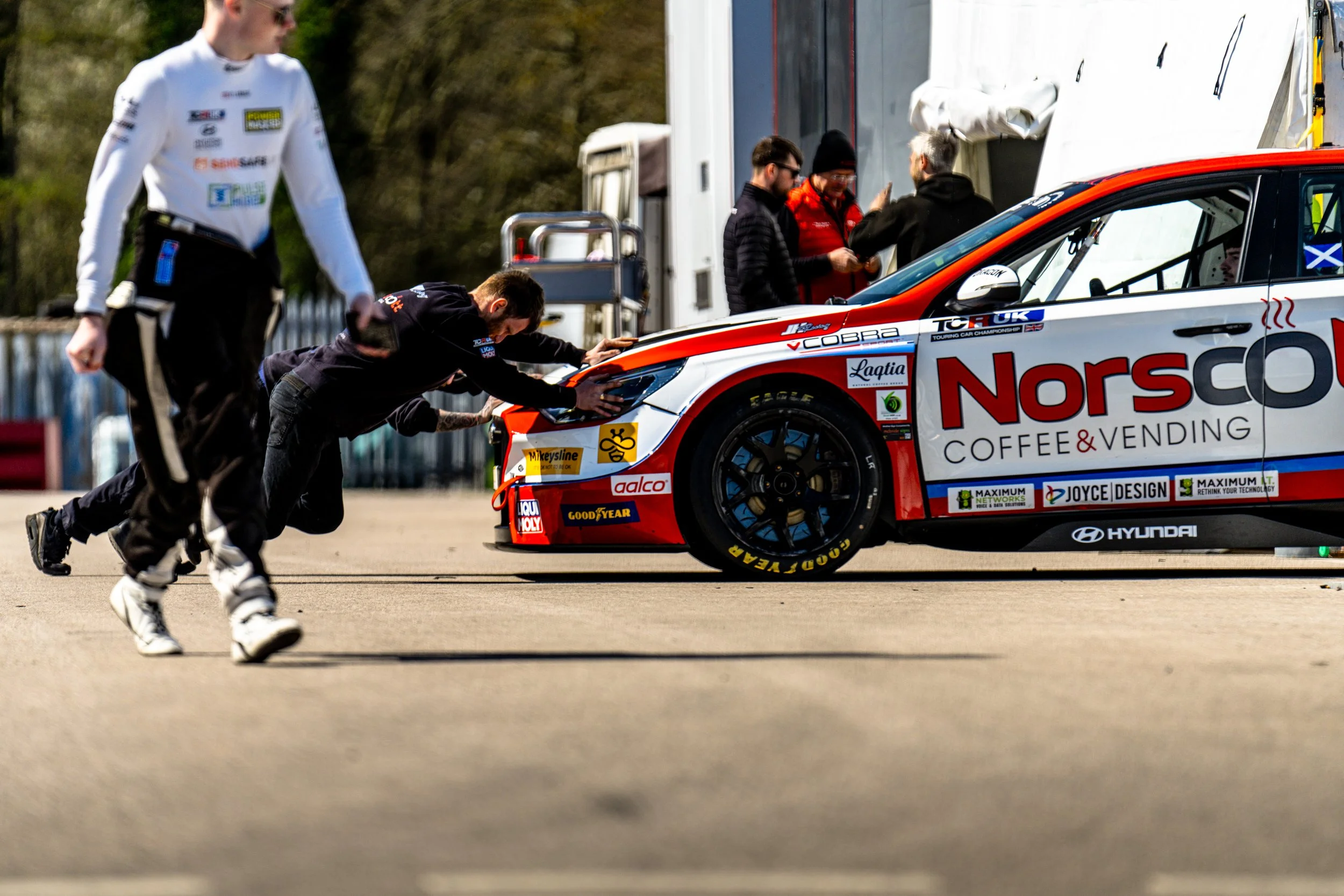 Race mechanics pushing a touring car back towards its garage
