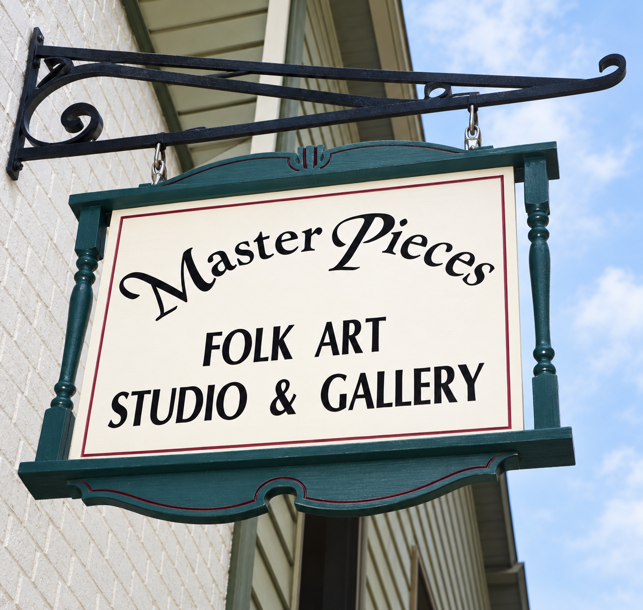 Restored Master Pieces sign with its teal frame and wrought-iron bracket against blue sky.