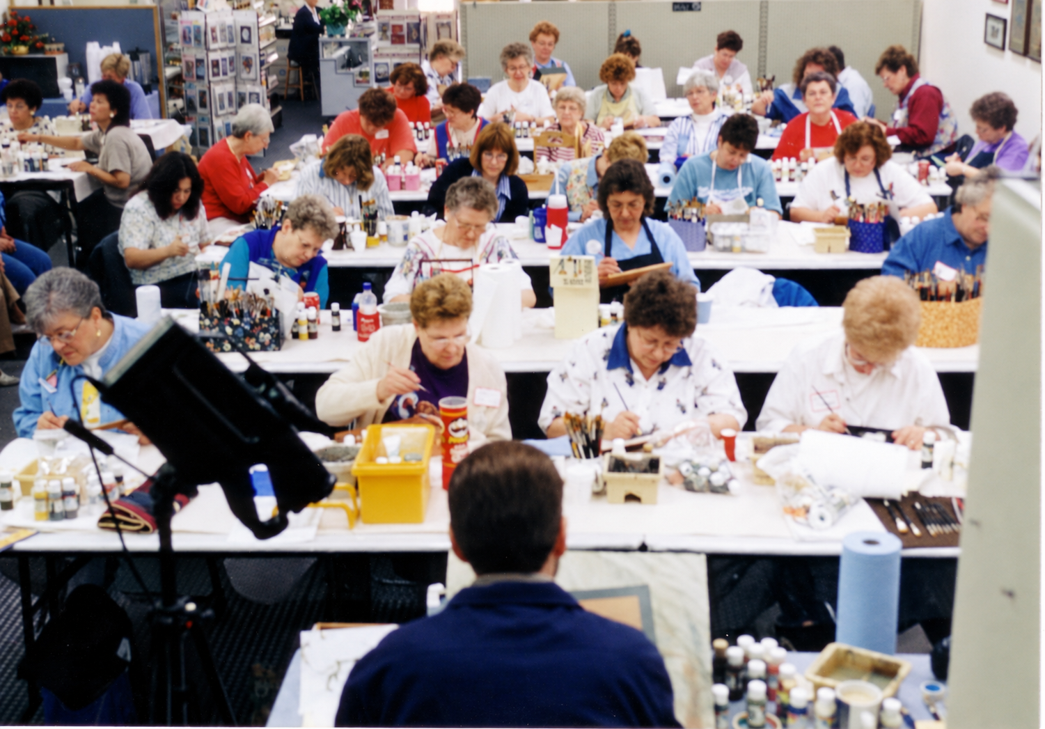 Rows of painting students seen from behind the instructor at Master Pieces.