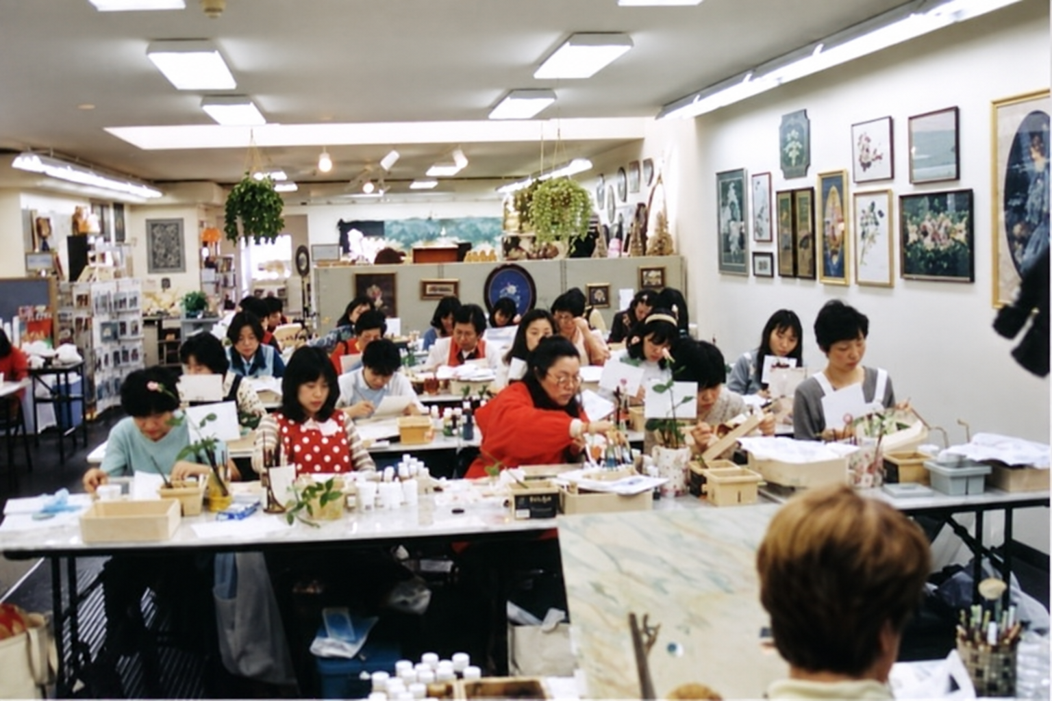 Japanese painting students, Betty in the foreground, a camera at upper right and part of another student at the far left.