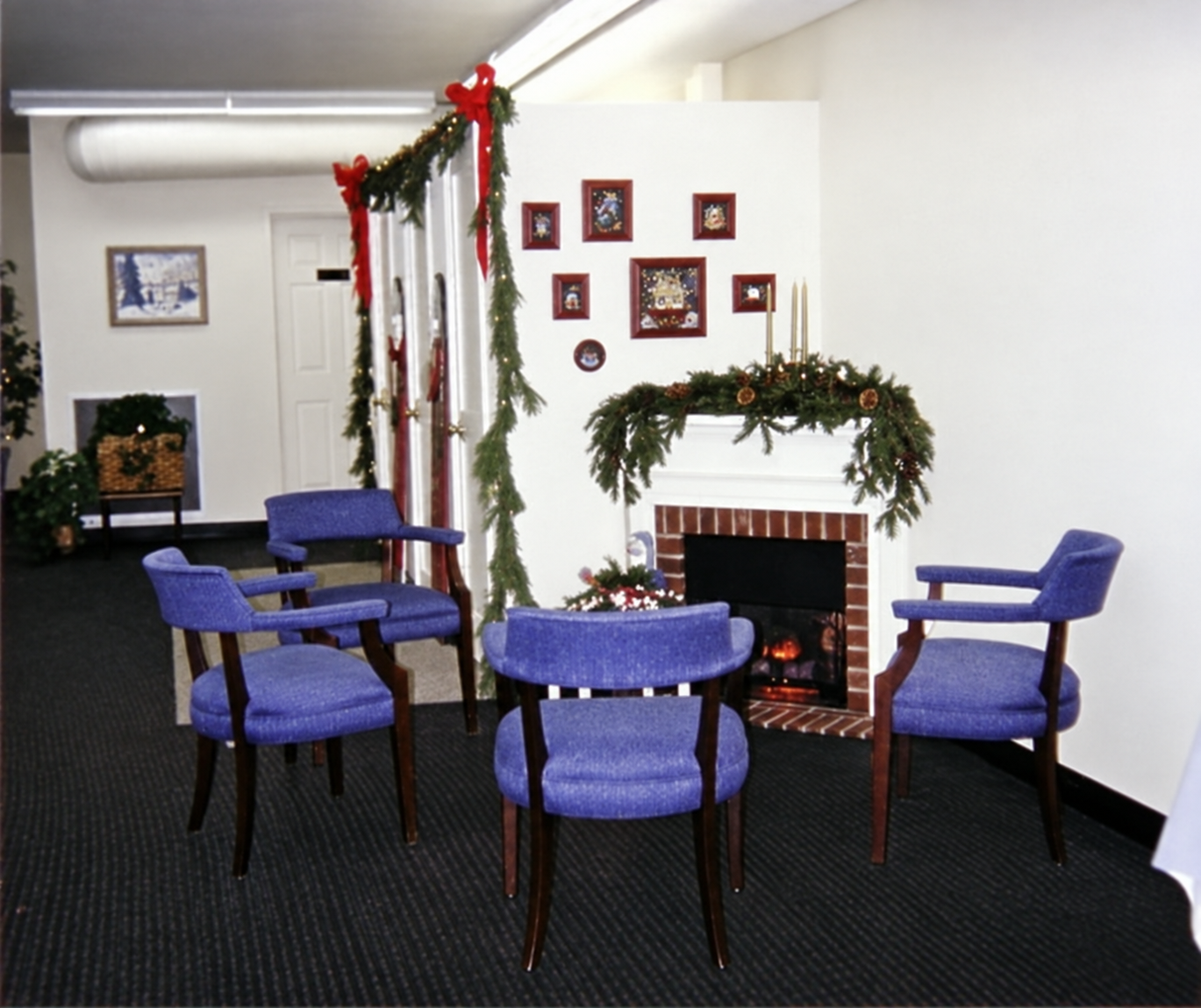 Blue chairs arranged beside the Christmas-decorated electric fireplace at Master Pieces.