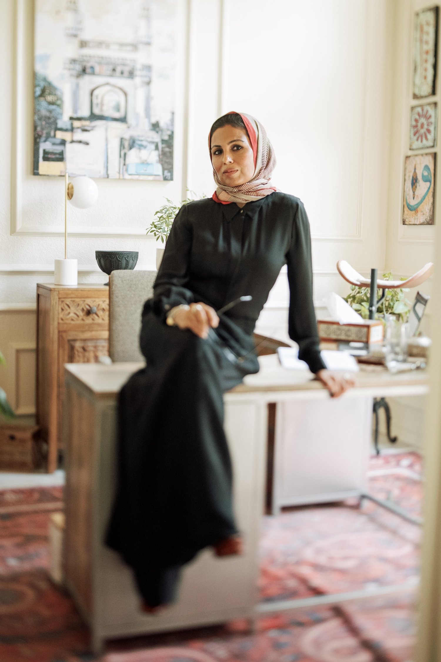 Dr. Farooqi seated on the edge of her desk in her office