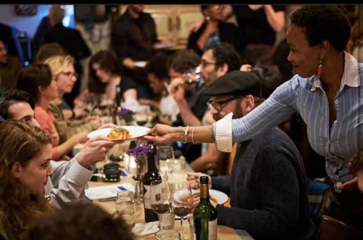 Sunday supper at Kaia: a plate handed down a long, full table