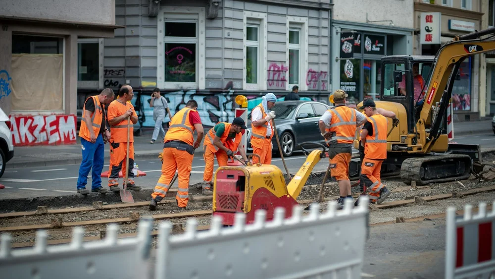 Bauarbeiter in orangefarbener Arbeitskleidung an einer Straßenbaustelle