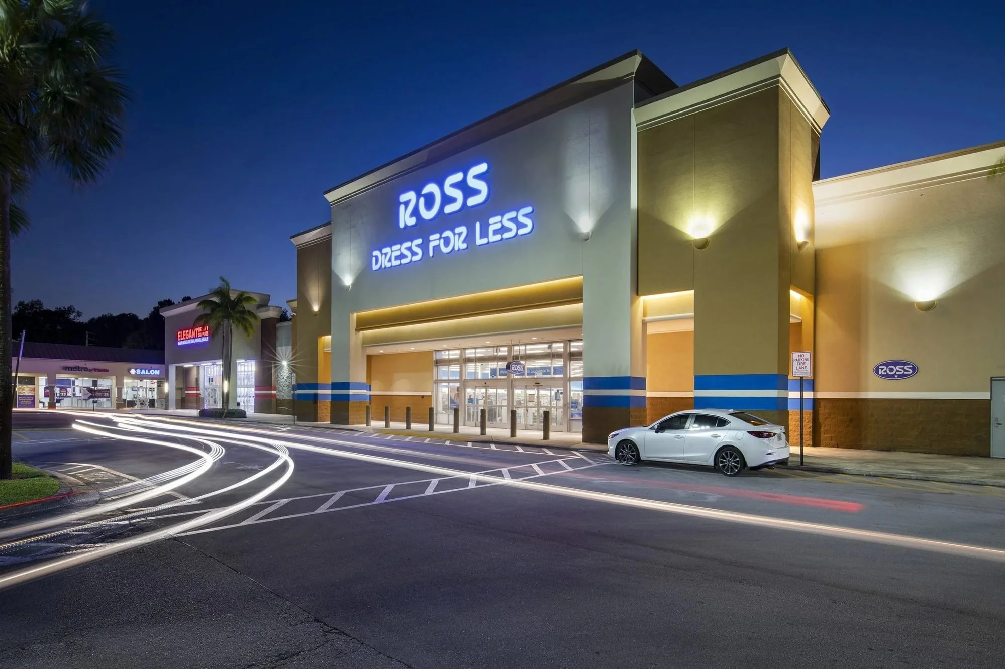 Single-tenant retail building at dusk with lit storefront signage
