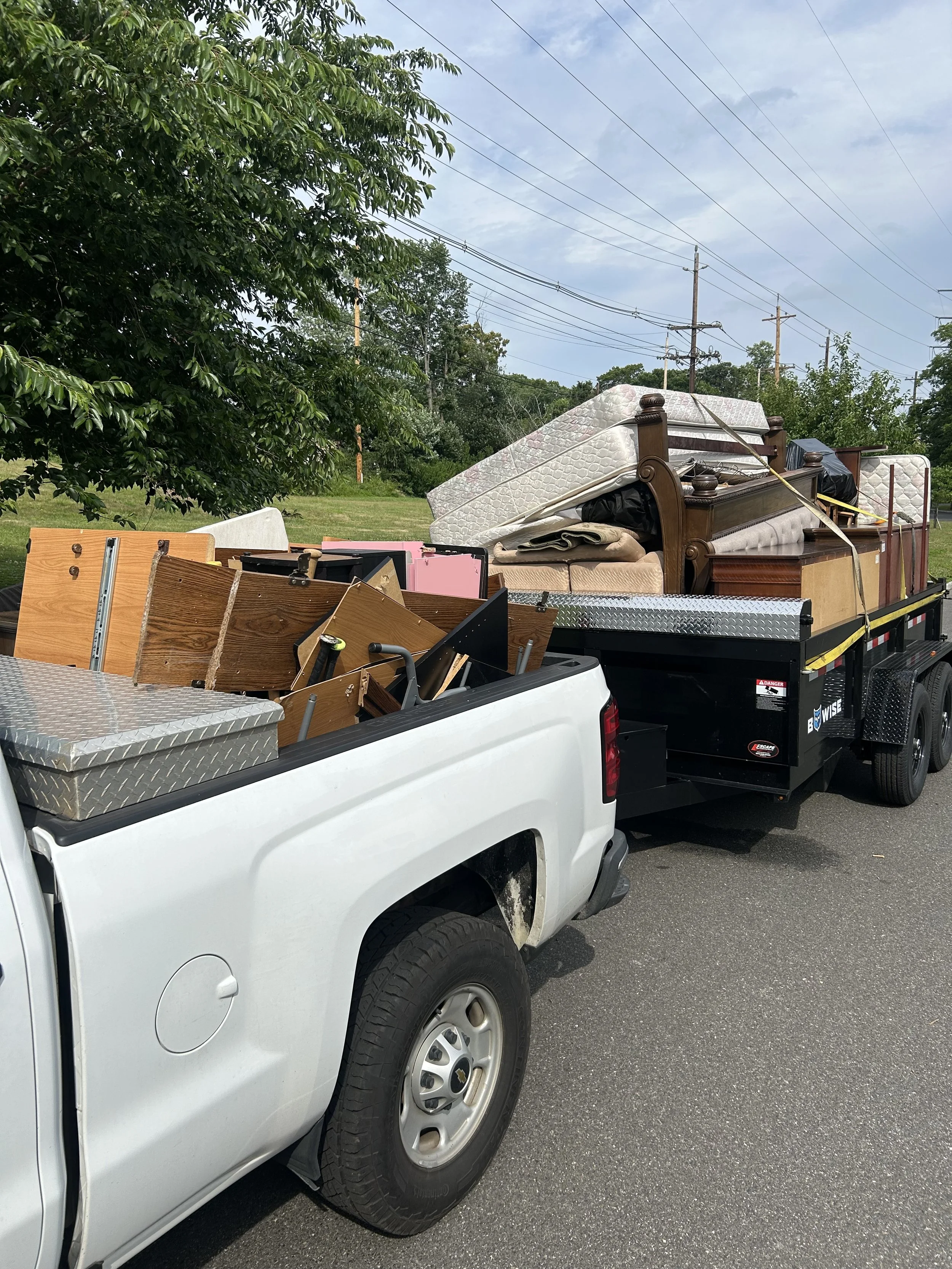 Truck and trailer loaded with furniture and mattresses for haul-away after a junk removal job