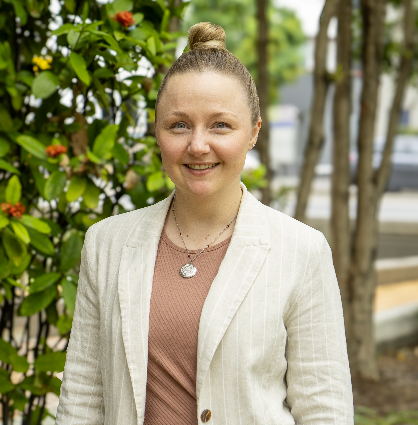 Jamie, founder of Lu, smiling outdoors in front of green leaves
