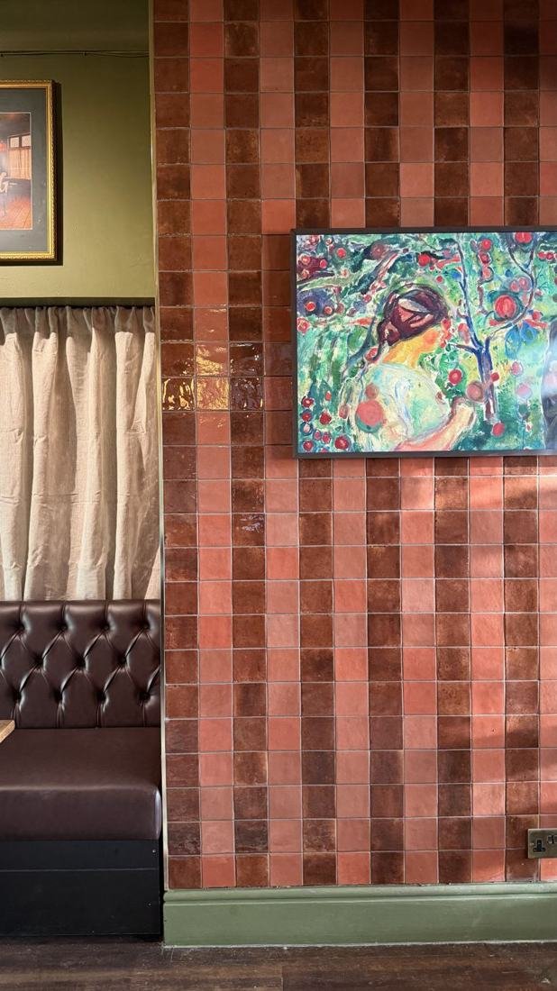 Terracotta tiled wall with artwork and leather seating in the Snug