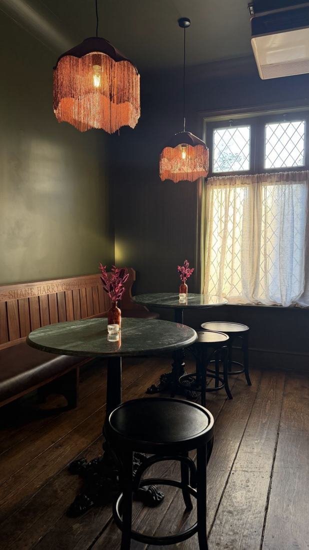 Round bistro tables under fringed pendant lights in the Snug