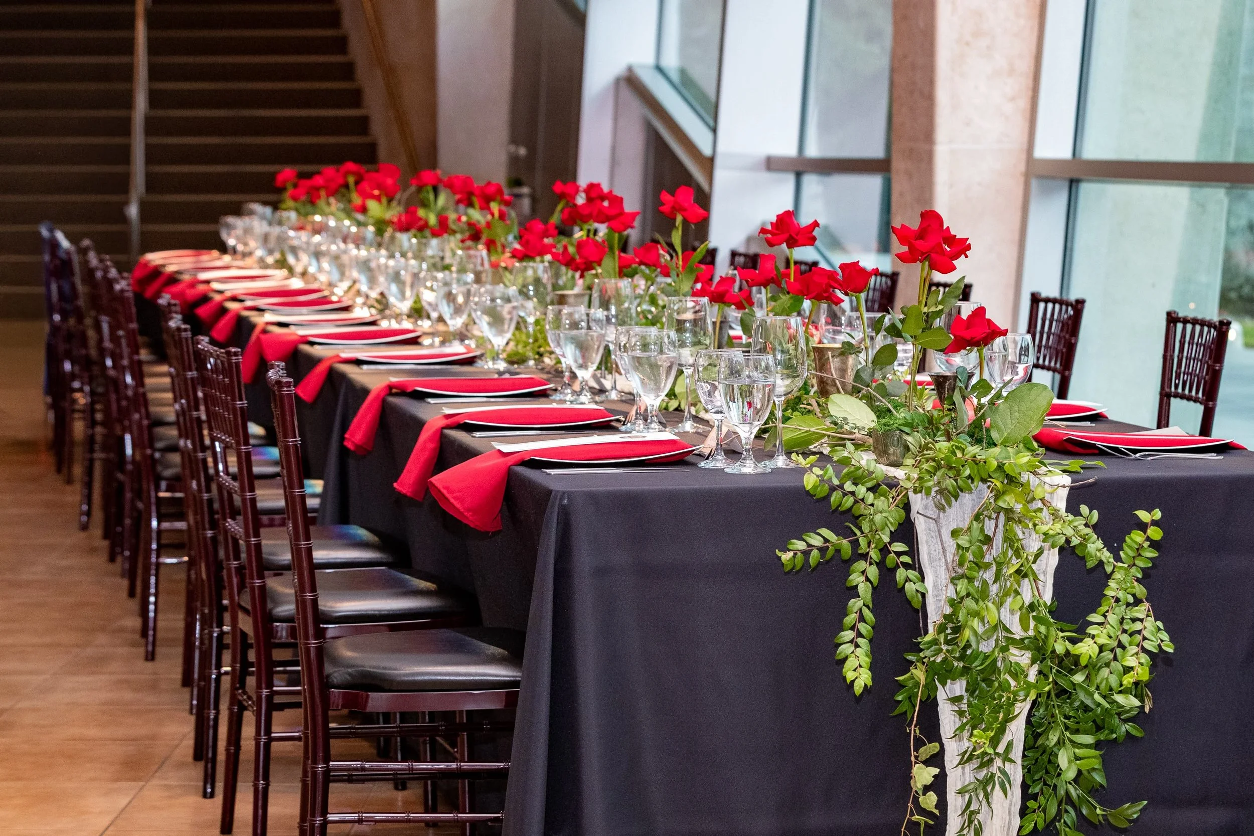 Pre-show dining table at Riverside Theatre, Vero Beach, with red roses and trailing greenery on black linen
