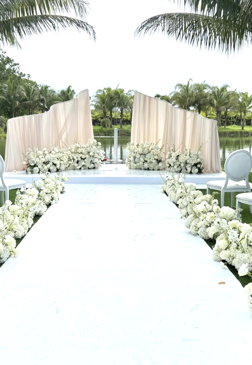 Outdoor ceremony aisle lined with white hydrangea and stock installations, waterfront Florida wedding