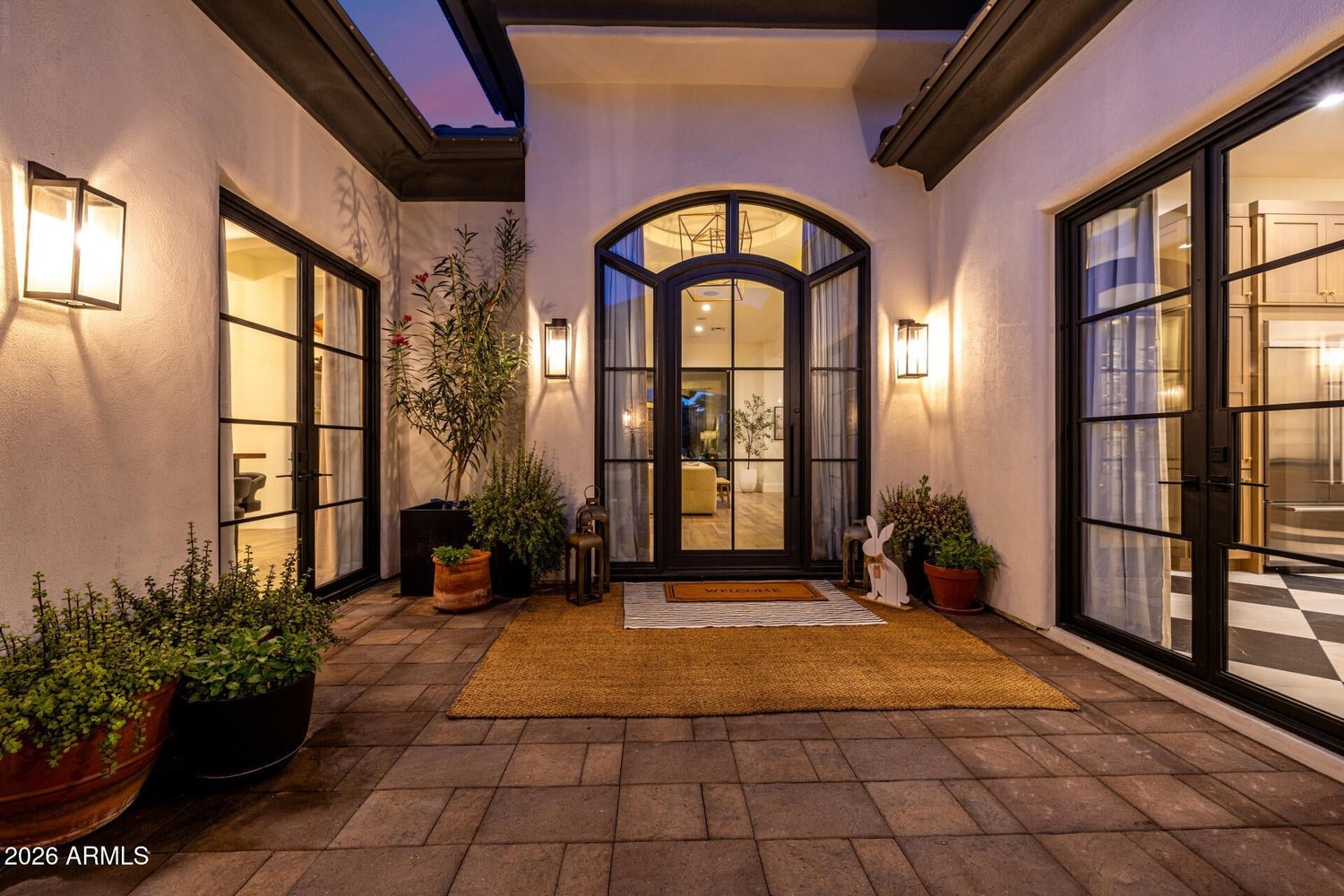 Courtyard entry with steel doors and lanterns at dusk