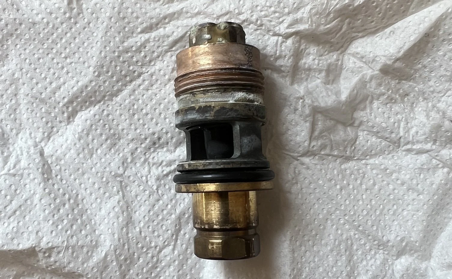 Diverter valve cartridge removed from a combi boiler, showing scale and corrosion around the seals