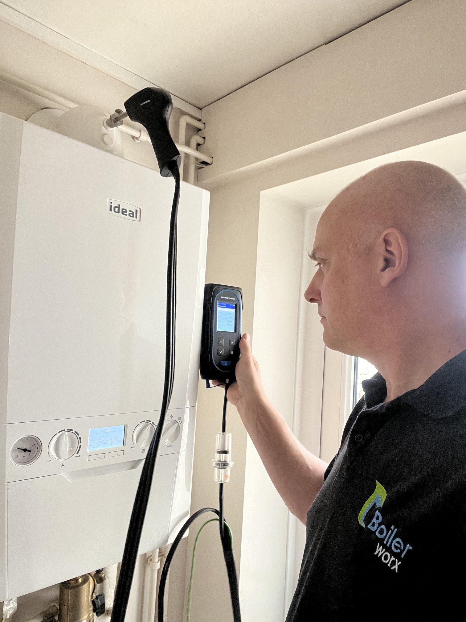 Gas Safe engineer carrying out a boiler service with a flue gas analyser