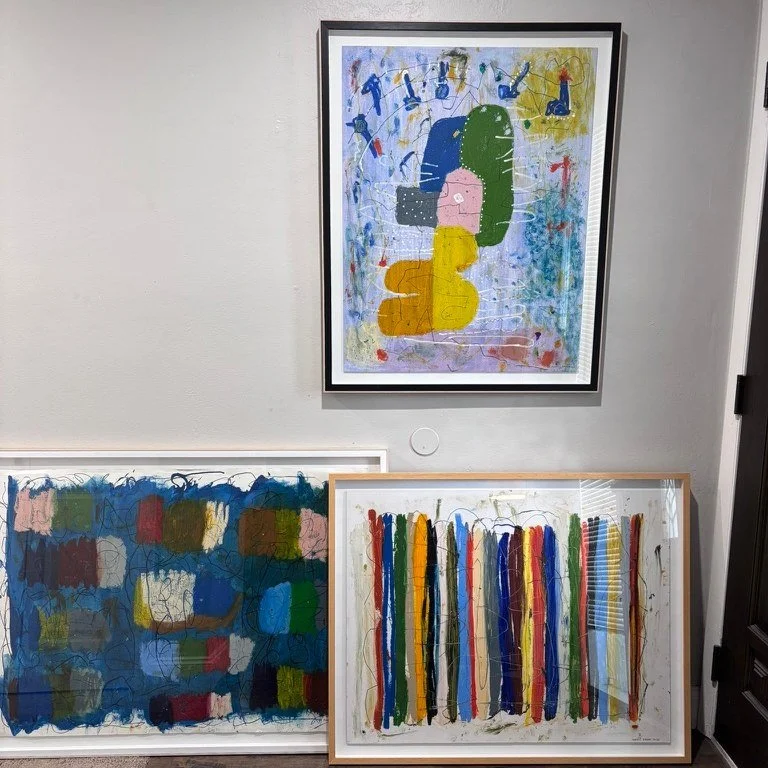 Three framed abstract paintings by Marcus Bacher displayed in a home interior.