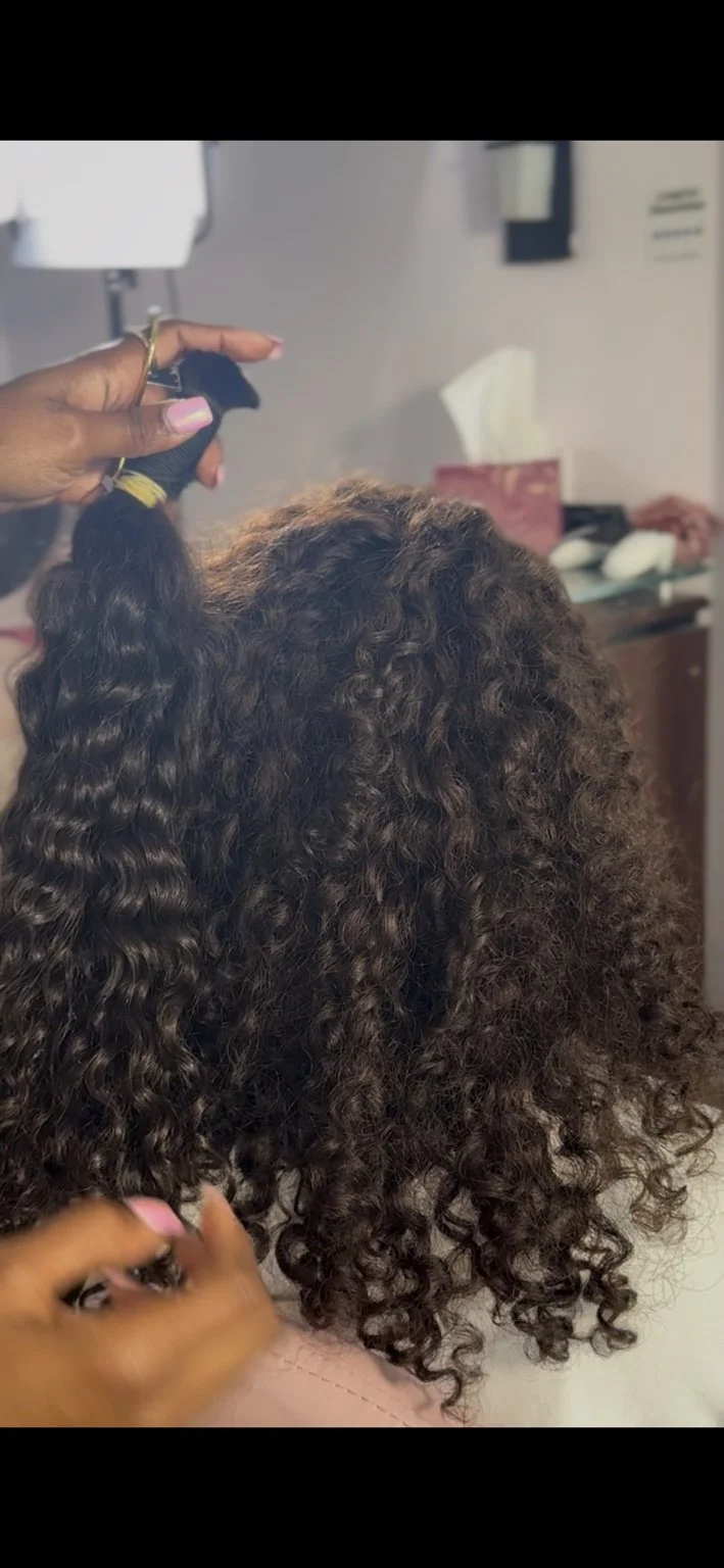 Octavia comparing a sourced curly ponytail directly beside a client’s natural curl pattern