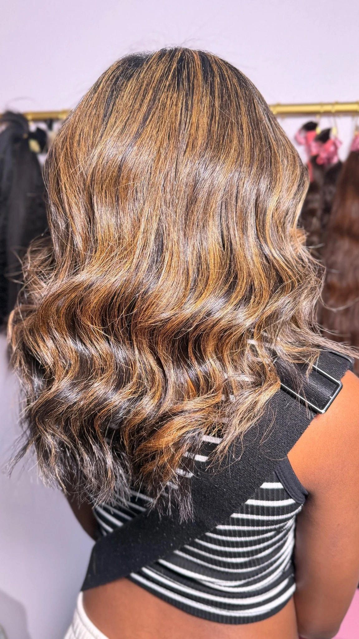Rear view of a shoulder-length dimensional brunette and caramel wavy finish