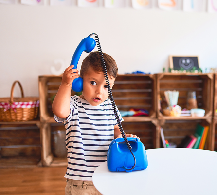 Toddler girl smiling while talking on a toy phone