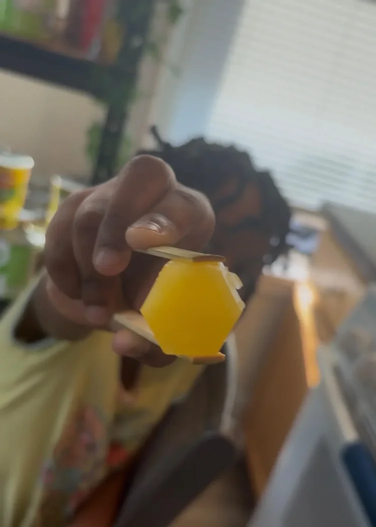 A golden yellow hexagon-shaped Freezy Bitez fruit treat held close to the camera