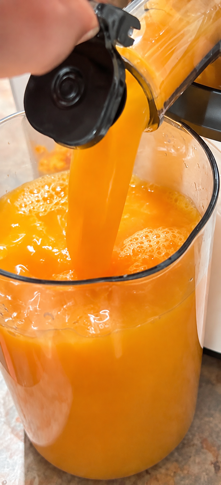 Bright orange fruit juice being poured into a jug