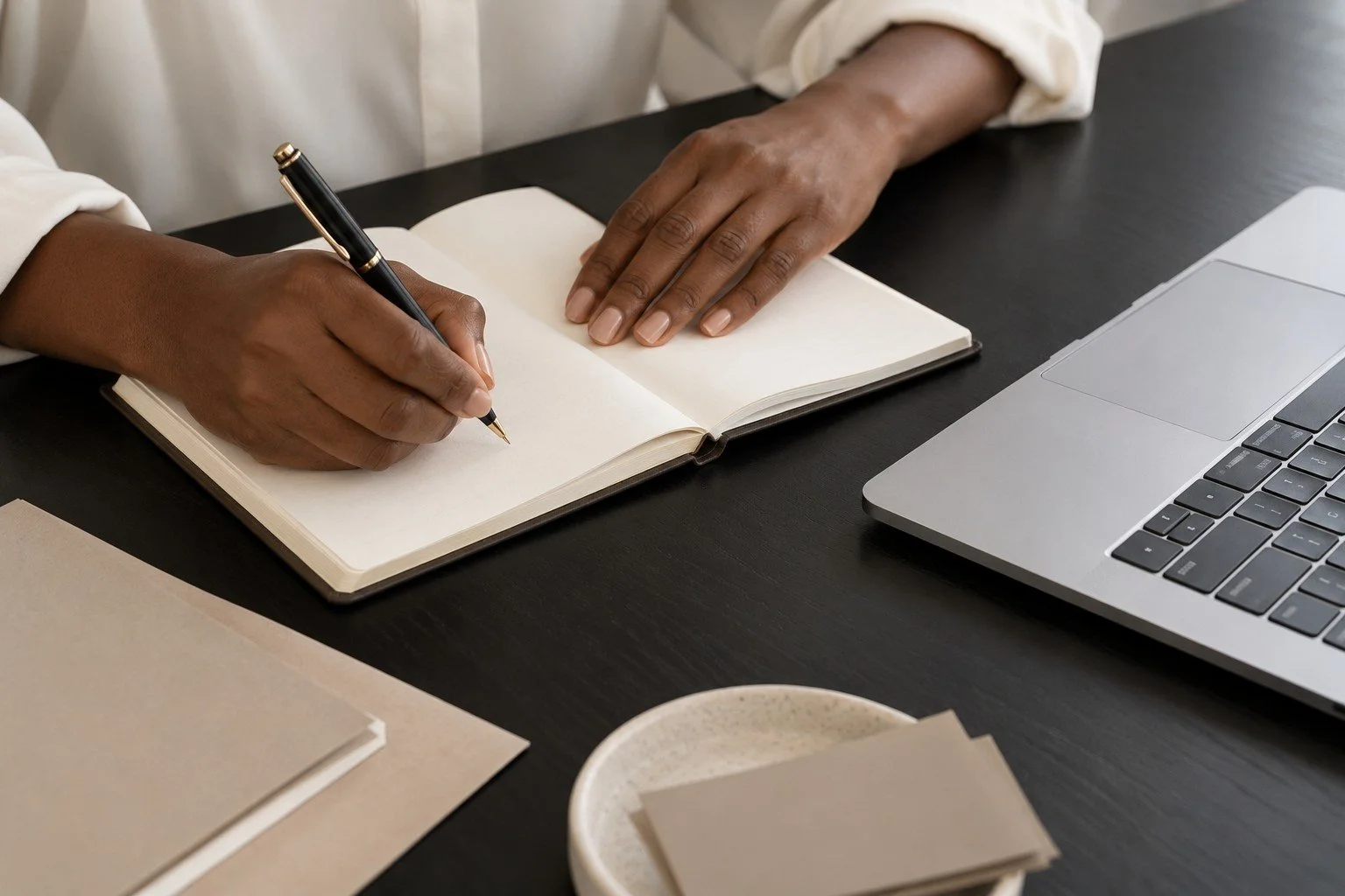 An organized workspace with a ledger, pen, and laptop