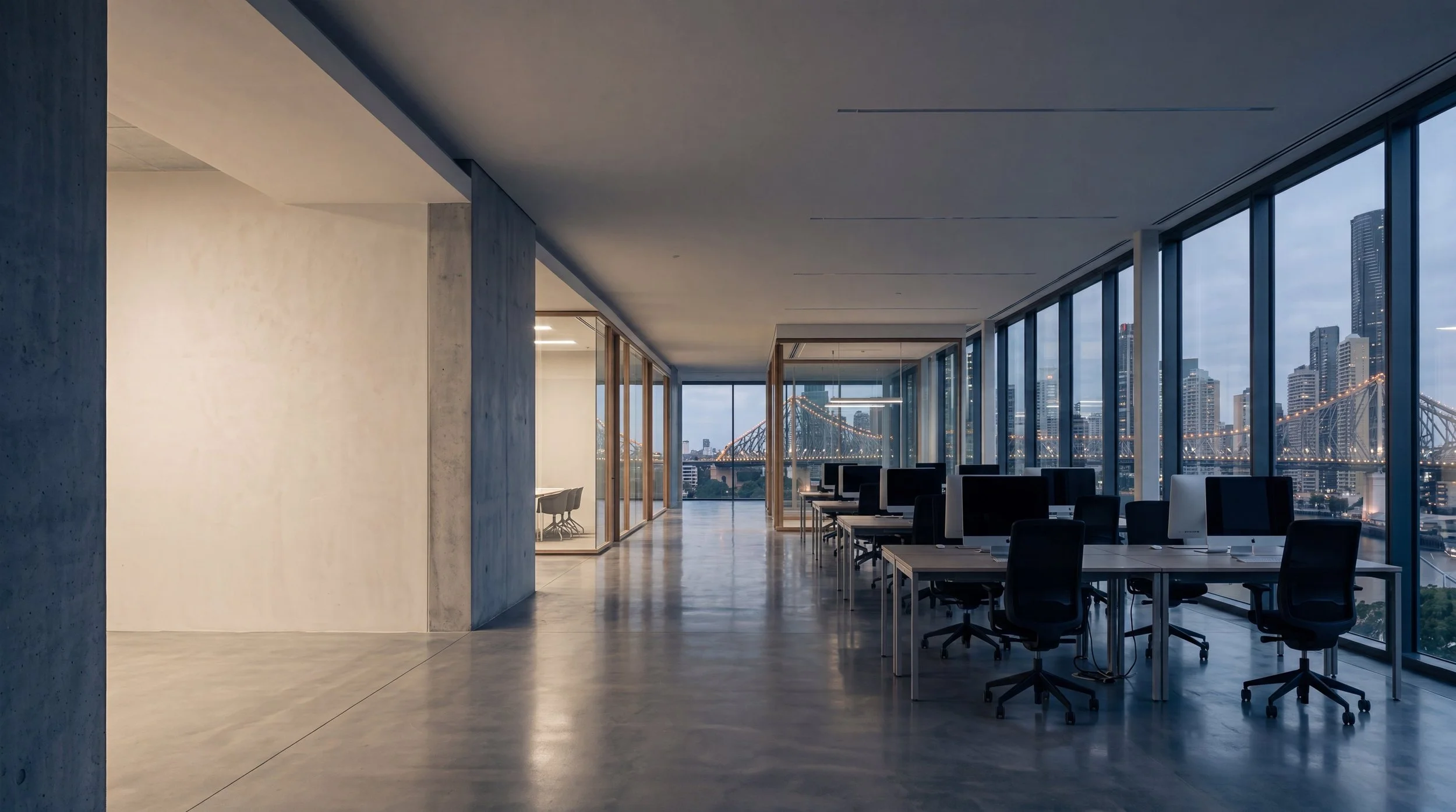 Empty Brisbane office at dusk with floor-to-ceiling windows overlooking the Story Bridge