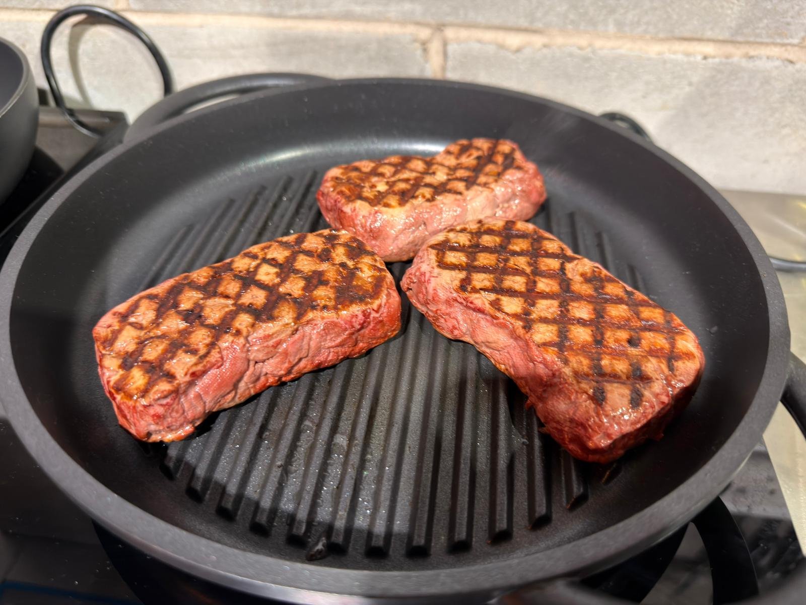 Three MycoStruct whole-cut protein pieces cooking in a grill pan