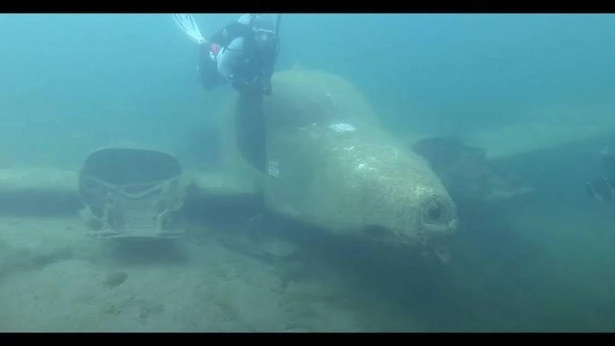 The sunken twin engine Cessna at Sand Hollow, seen nose on with both wings resting on the bottom and a diver finning above the fuselage