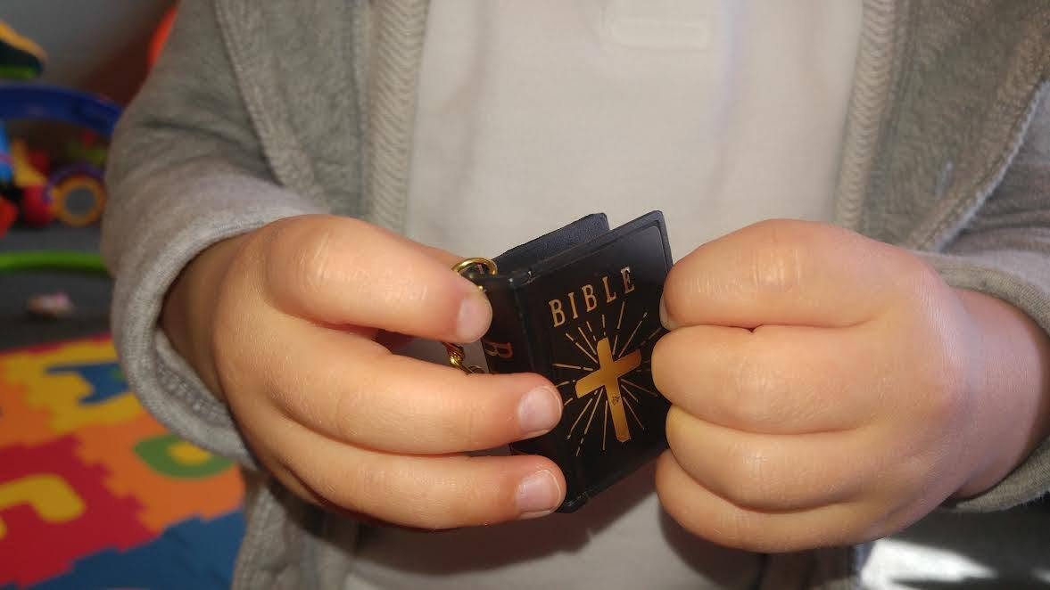 Child holding a small Bible