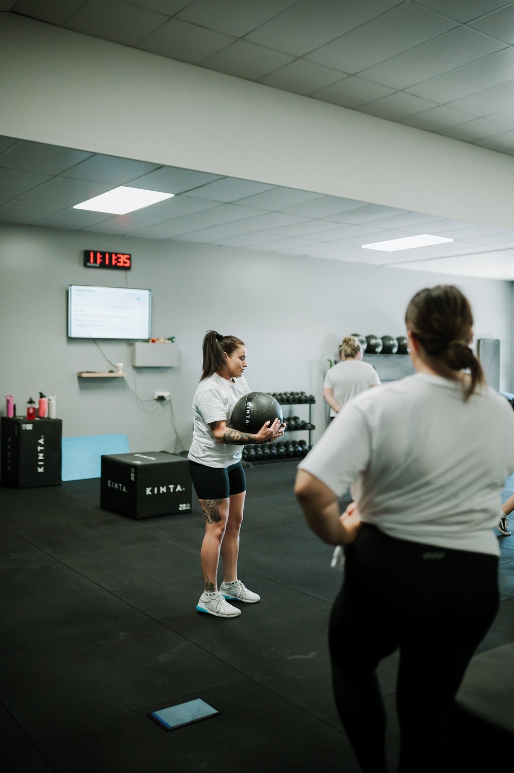 A coach demonstrating a medicine ball movement in a small group session
