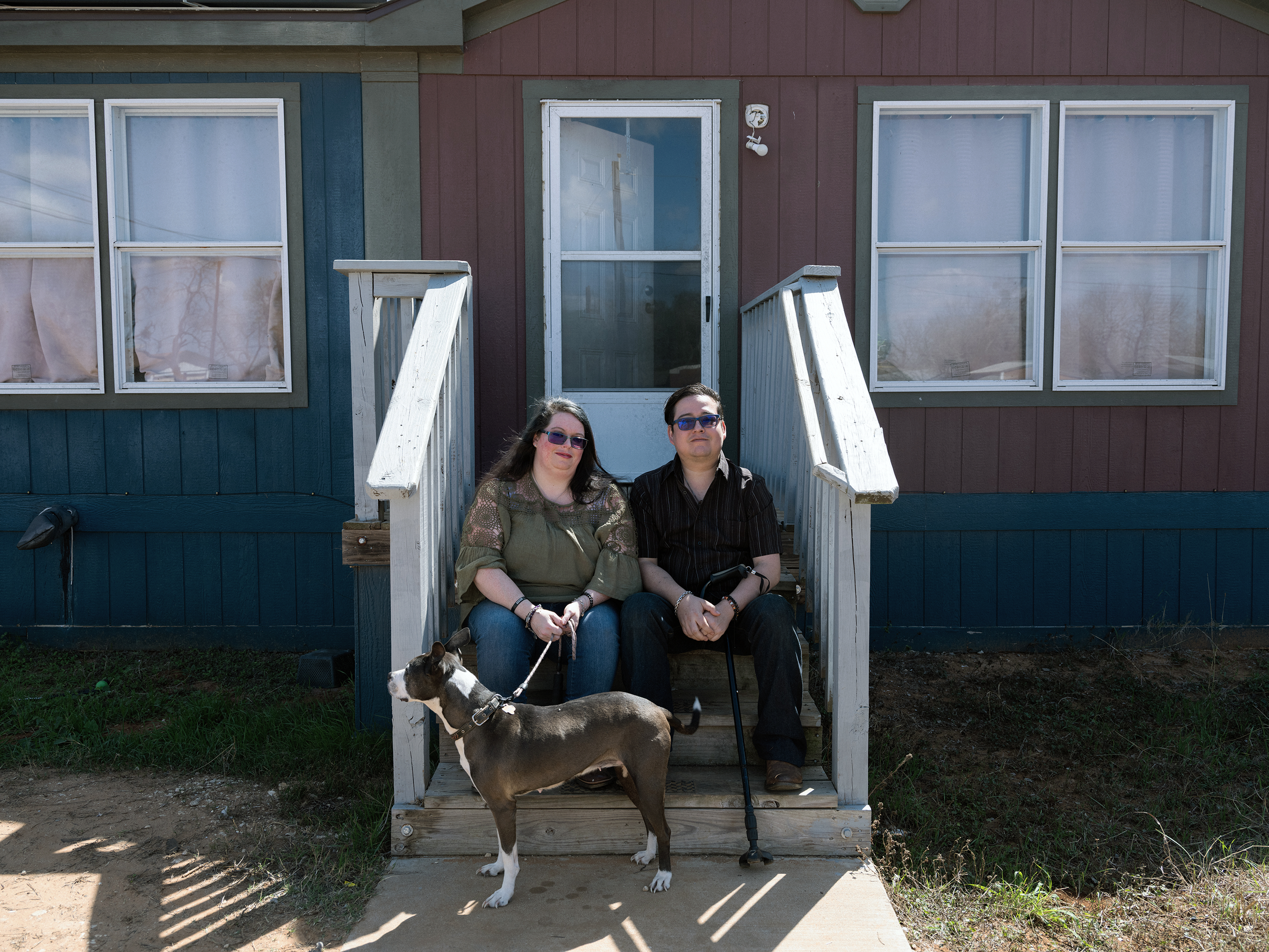 Jacqueline stands in the doorway of her North Carolina home, dressed in bright pink, on a sunny porch.
