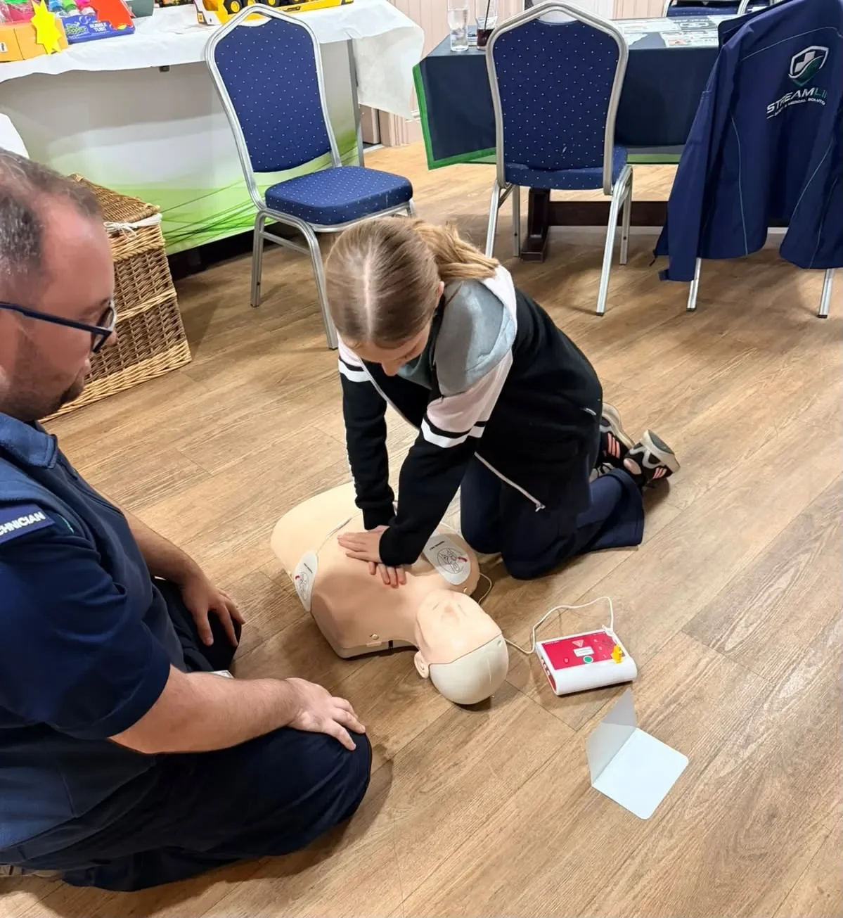An instructor guiding a learner practising CPR on a training manikin