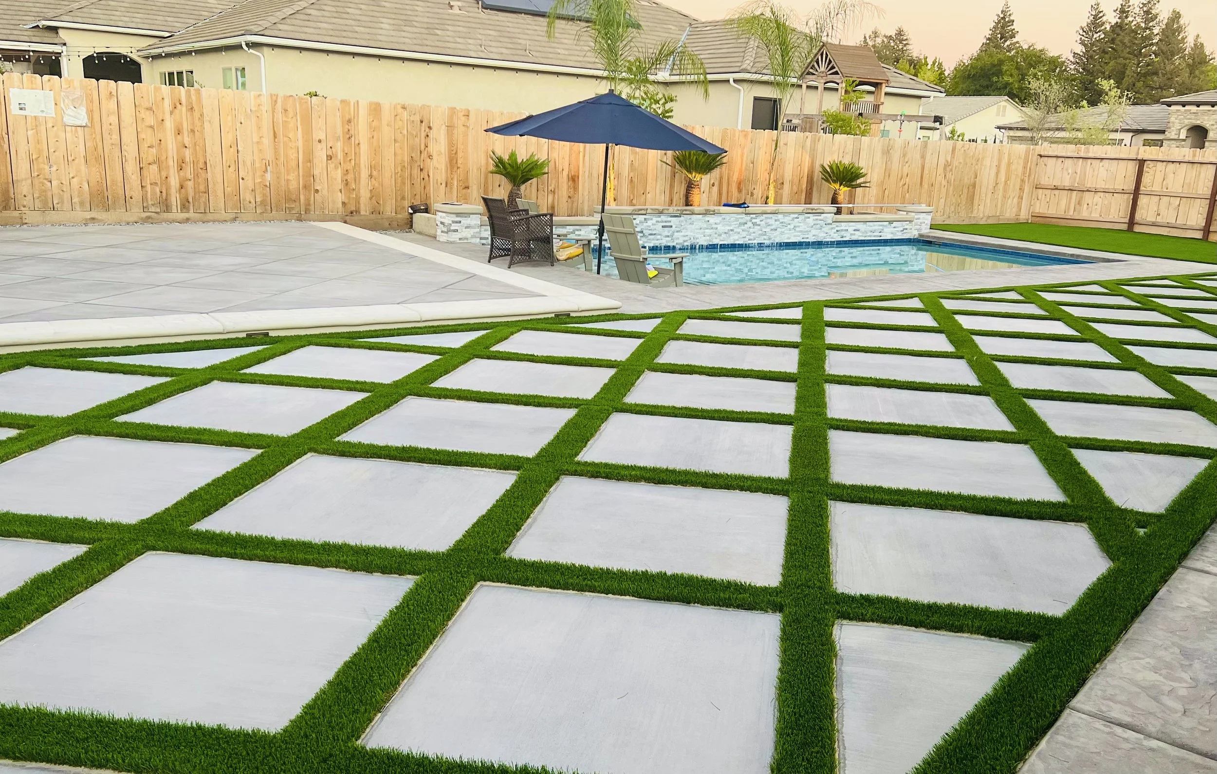 Paver-and-turf grid patio beside a pool, built by Specialty Landscape
