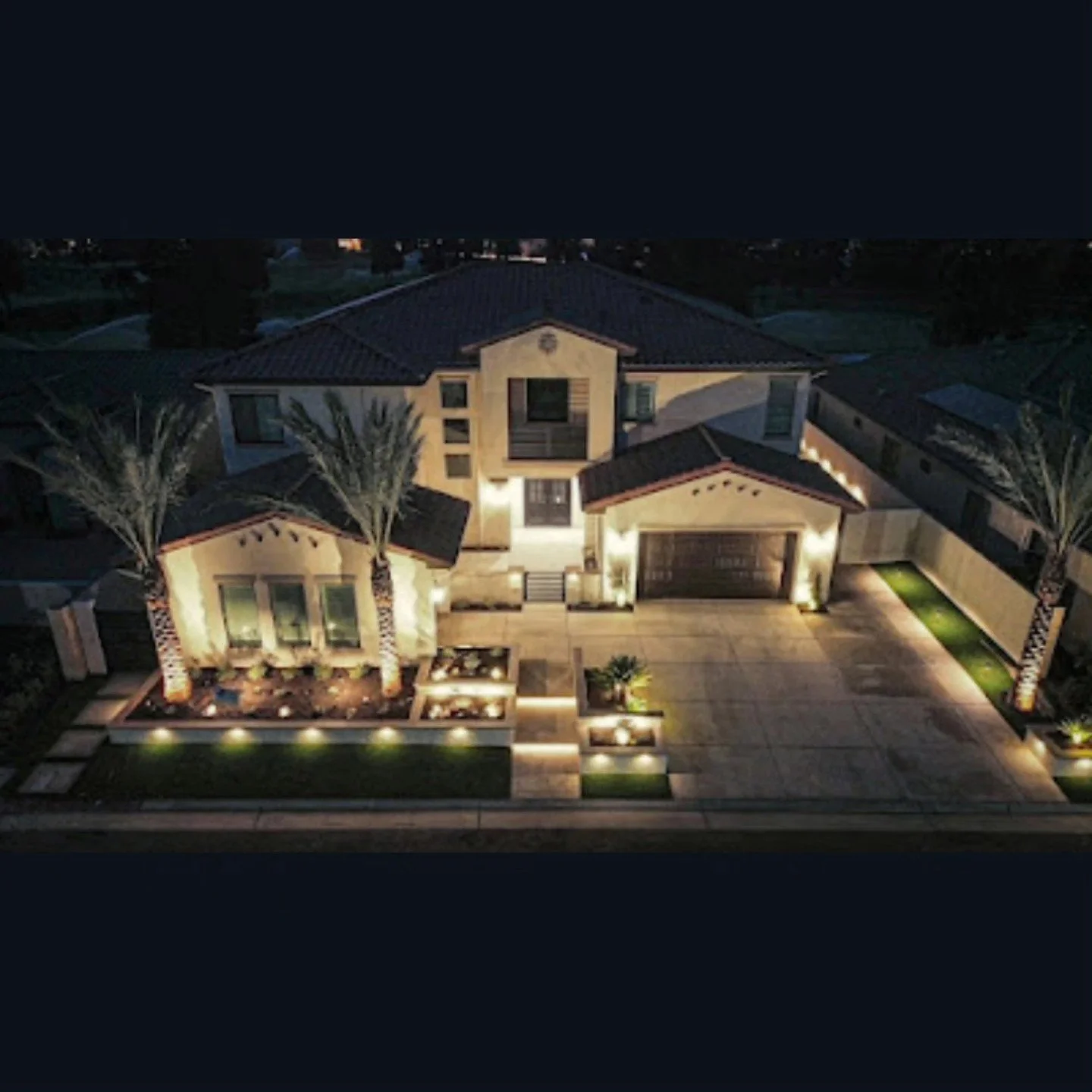 Home front lit at night with landscape lighting by Specialty Landscape in Kerman