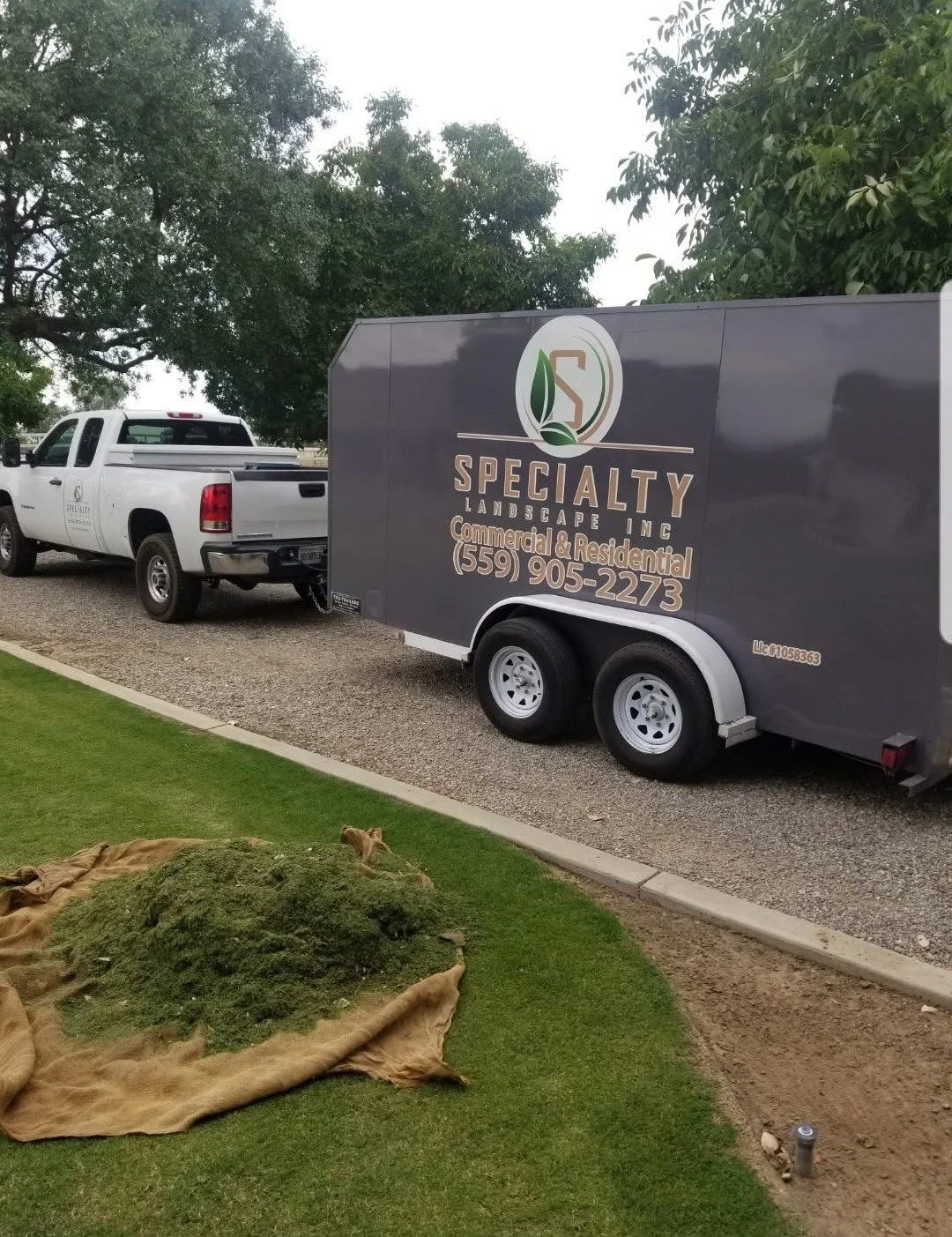 Specialty Landscape branded truck and equipment trailer parked at a job site