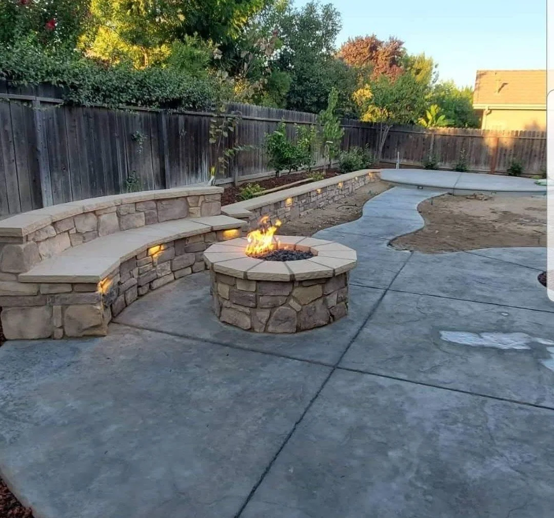 Gas fire pit and stone seat wall on stamped concrete by Specialty Landscape in Kerman