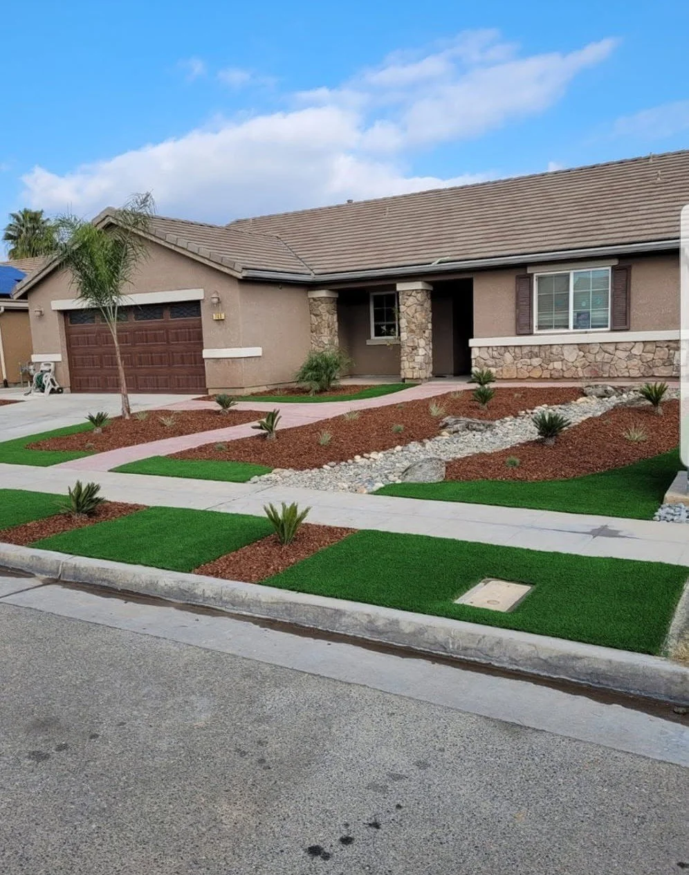 Finished front yard with artificial turf strips, stone borders and mulch beds