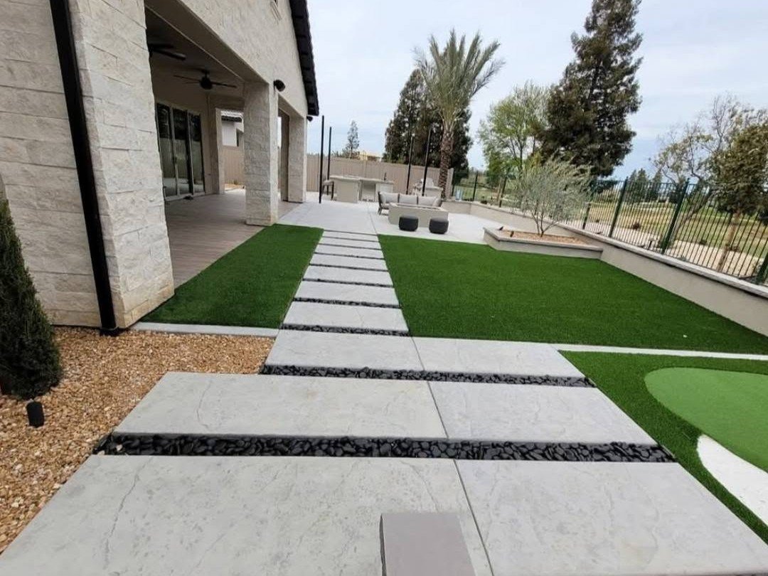 Paver-and-turf grid patio with a shaded dining area, built by Specialty Landscape
