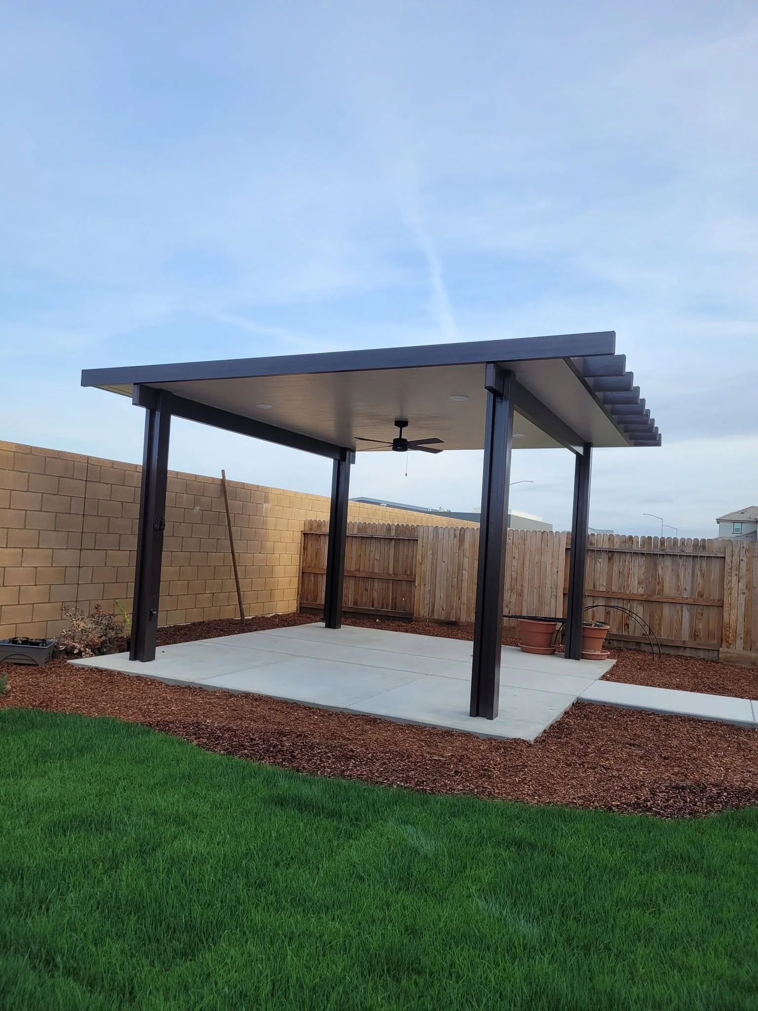 Finished Alumawood patio cover with a ceiling fan installed by Specialty Landscape in Kerman
