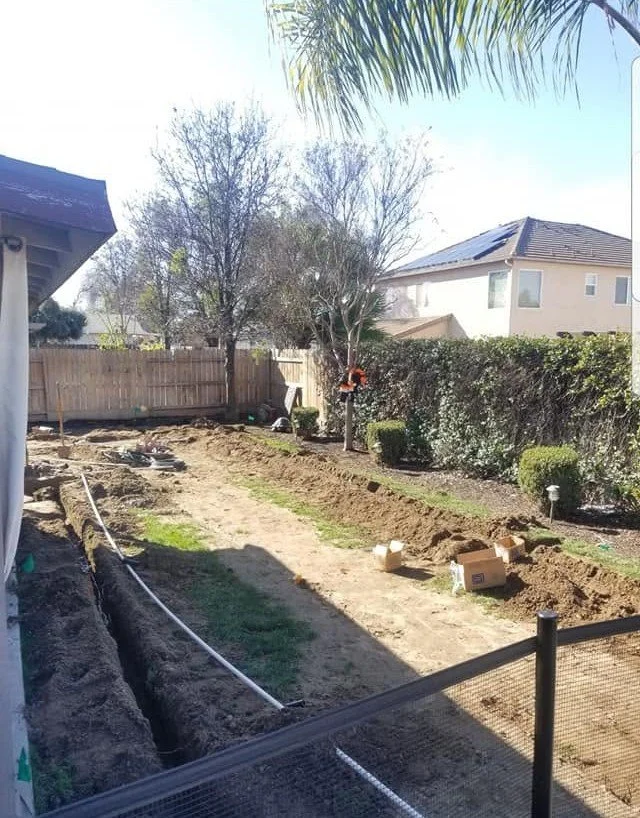 Irrigation trenching across a backyard by Specialty Landscape