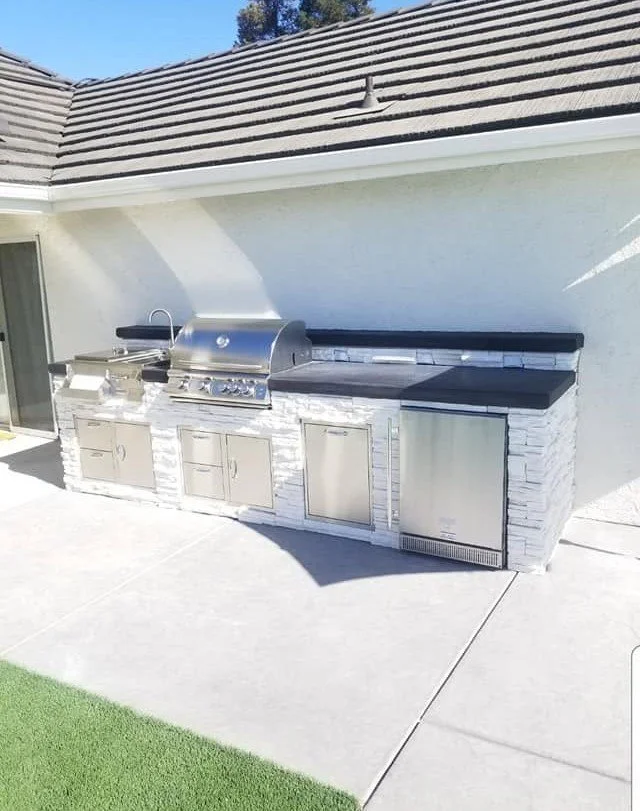 Outdoor kitchen with a built-in stainless grill and stone-veneer island