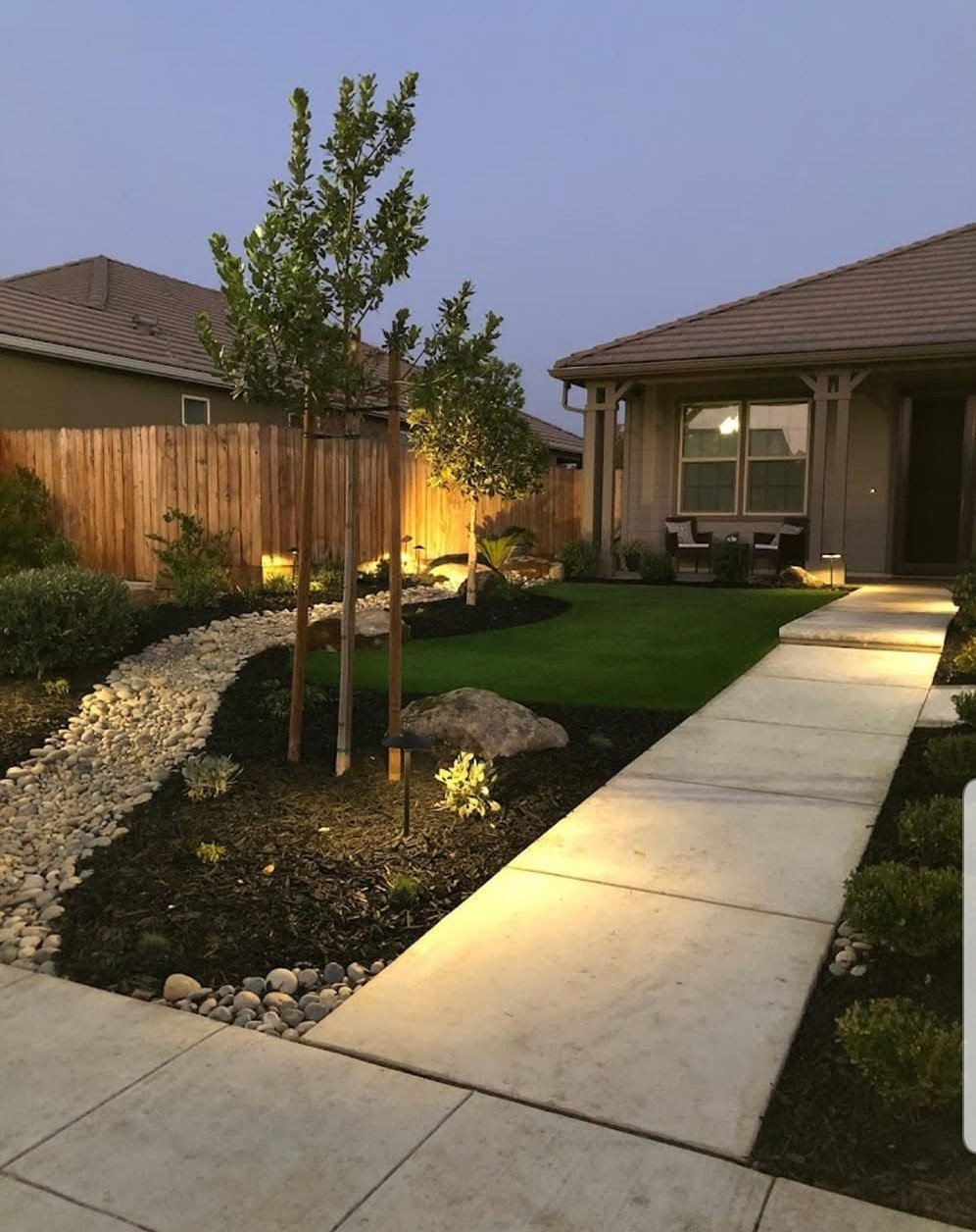 Front yard at dusk lit by low-voltage landscape lighting from Specialty Landscape