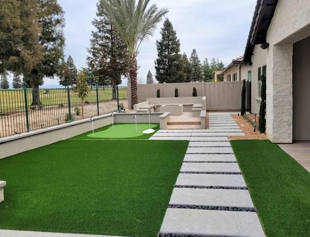 Block wall and paver patio bordering backyard turf by Specialty Landscape in Kerman