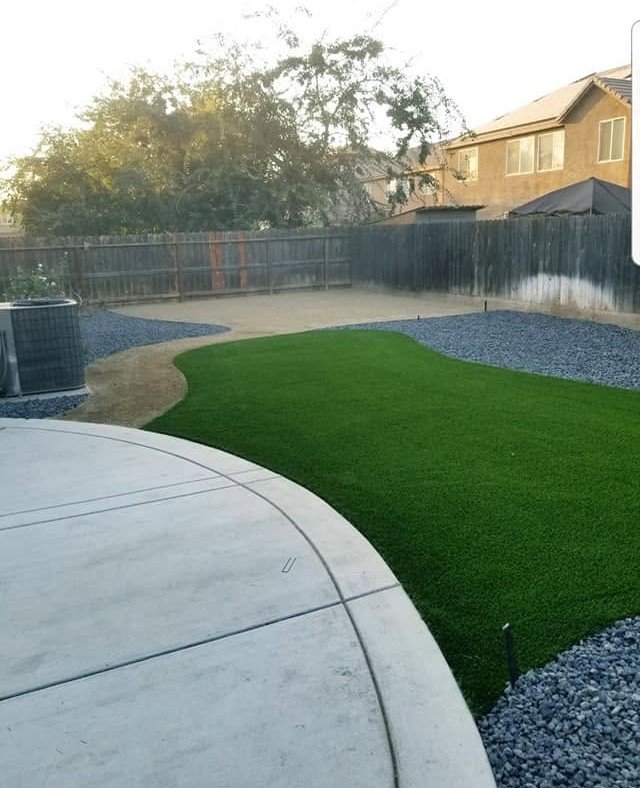 Low-maintenance backyard turf with a gravel border in Lemoore by Specialty Landscape