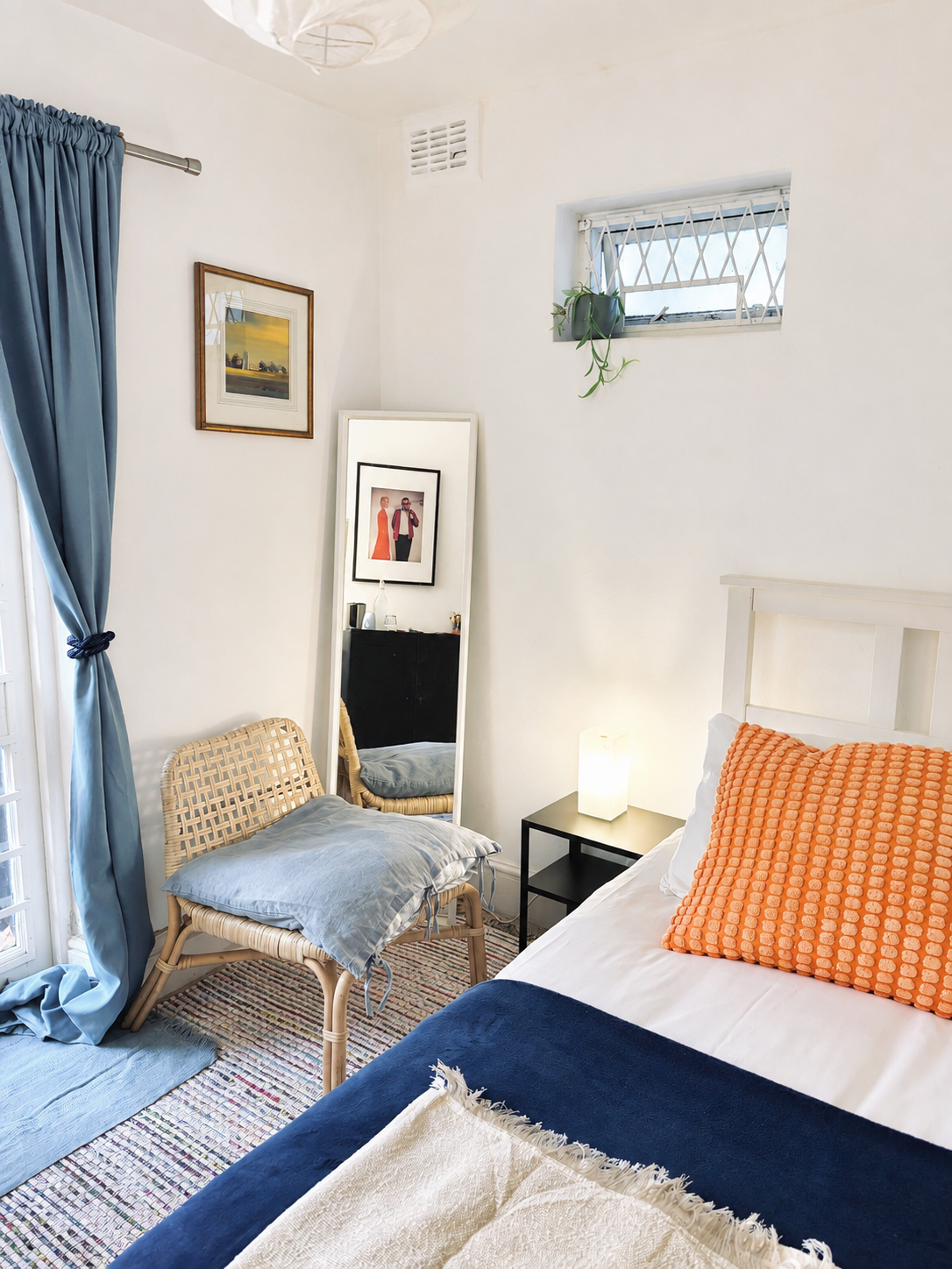 Room 8 single bedroom with navy throw, orange cushion and blue curtains at Central Victorian House in Camden Town