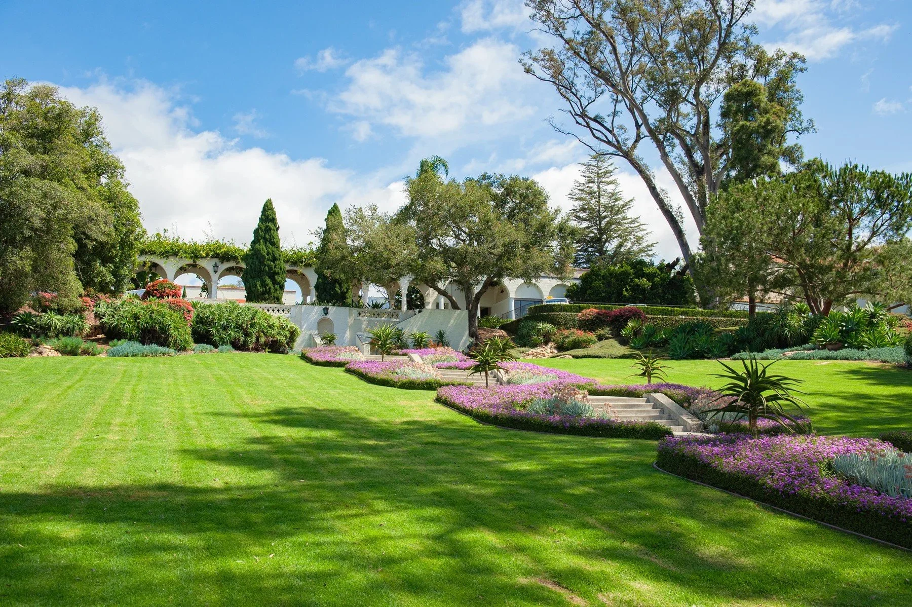 Sweeping lawns and colorful planting beside steps and white arches at Riviera Park